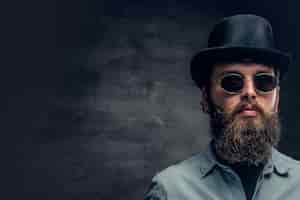 Free photo portrait of serious, bearded male in sunglasses and cylinder hat.