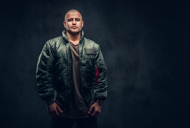 Portrait of a serious brutal male in casual clothes on a dark background.