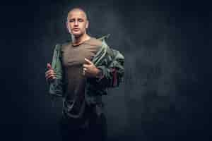 Free photo portrait of a serious brutal male in casual clothes on a dark background.