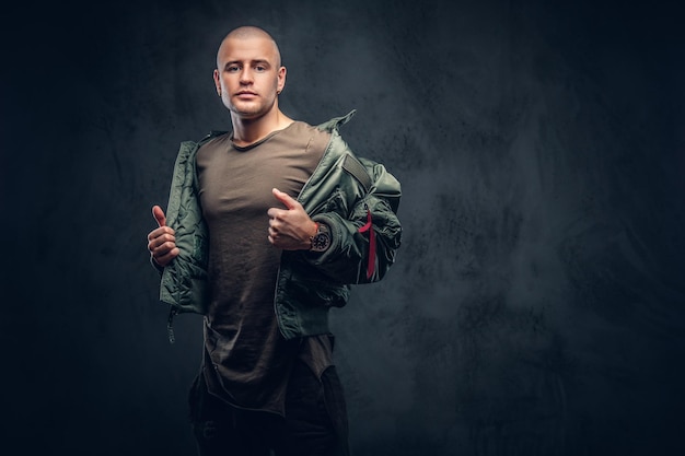 Portrait of a serious brutal male in casual clothes on a dark background.