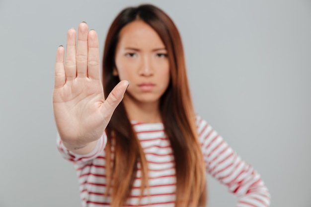 Free photo portrait of a serious confident woman showing stop gesture