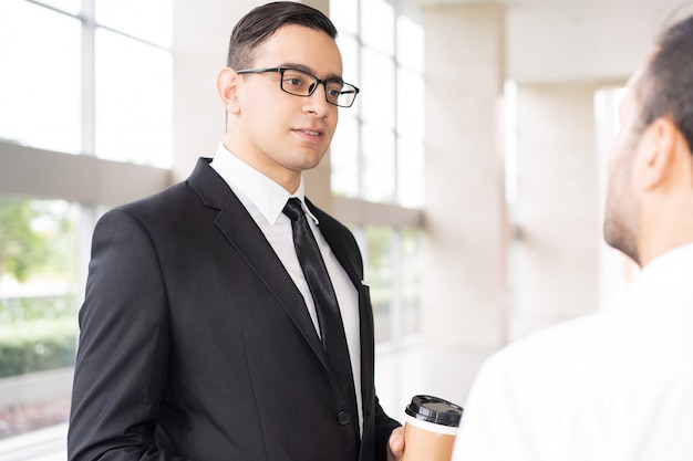 Portrait of serious executive in glasses listening to employee