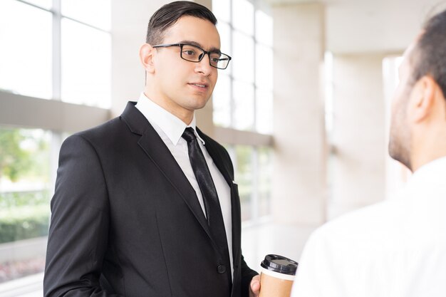 Portrait of serious executive in glasses listening to employee