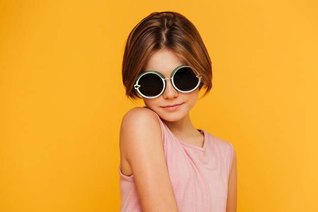 Портрет серьезной девушки в солнечных очках смотря камеру