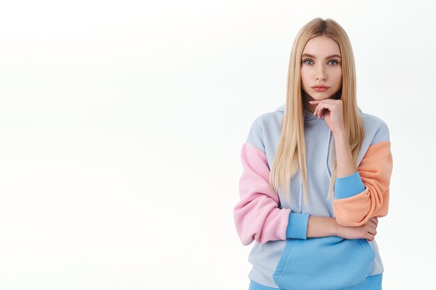 Portrait of serious-looking, determined smart attractive girl with long blond hair, looking interested and thoughtful