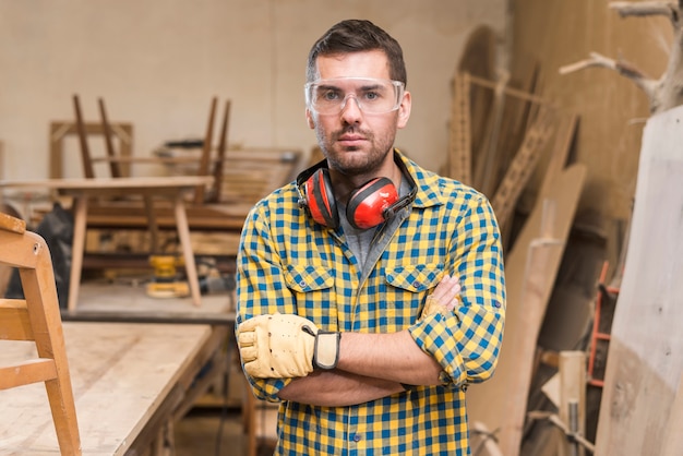 Portrait of a serious male carpenter standing in the workshop