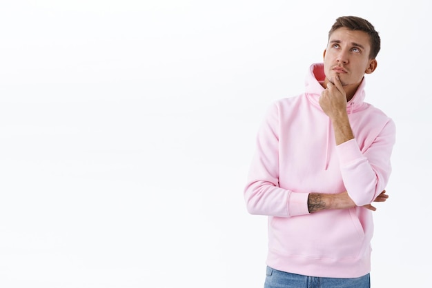 Portrait of serious thoughtful blond man looking up perplexed touching chin thinking about something important making decision pondering between choices imaging plan white background