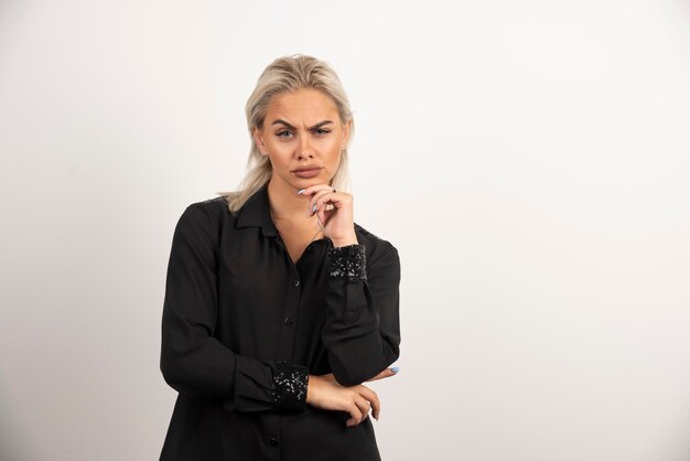 Portrait of serious woman in black shirt posing on white background. High quality photo