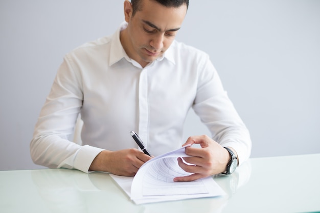 Portrait of serious young businessman filling in questionnaire