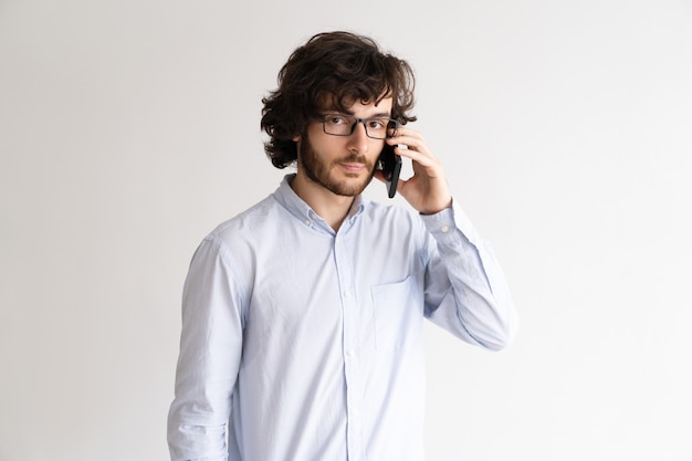 Портрет серьезного молодого человека в очках, говорить на мобильном телефоне.
