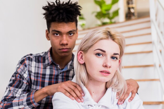 Portrait of a serious young man with his girlfriend looking at camera