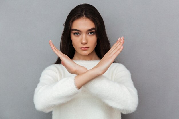 Portrait of a serious young woman showing crossed hands gesture