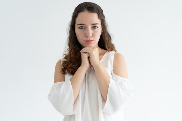 Portrait of serious young woman standing with her hands clasped