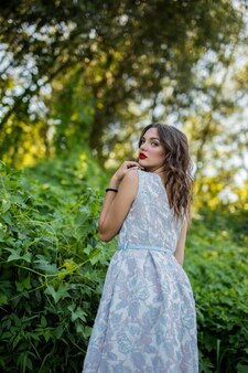 Ritratto di una ragazza bruna sexy in natura che si guarda alle spalle con un vestito estivo leggero Foto Gratuite