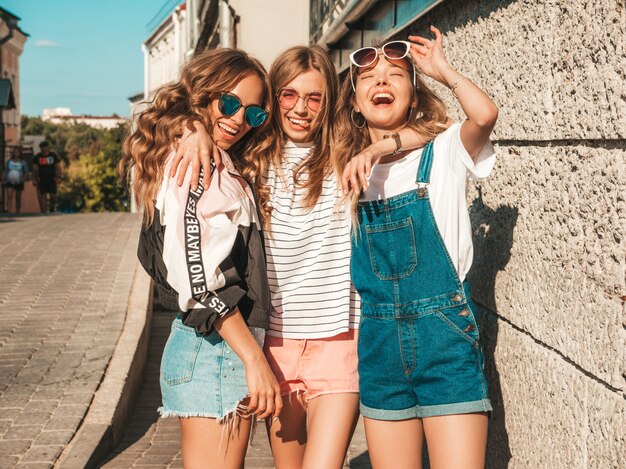 Portrait of  Sexy carefree women posing on the street background.Positive models having fun in sunglasses.Hugging