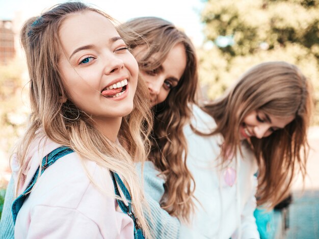 Portrait of  Sexy carefree women posing on the street background.Positive models having fun.Winking and shows tongue