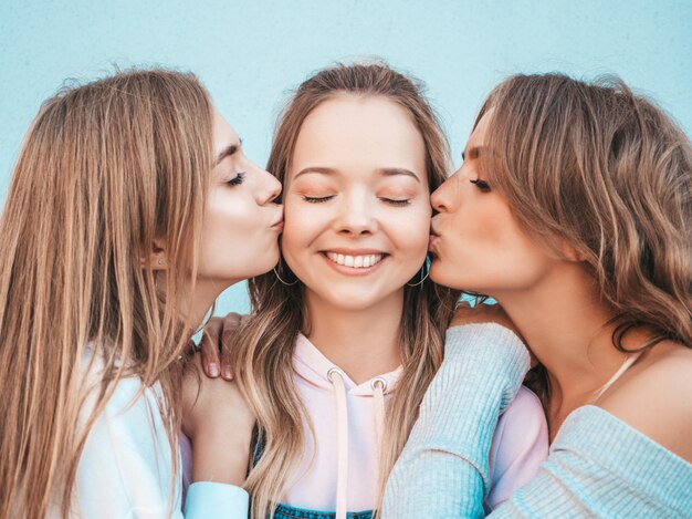 Portrait of  Sexy carefree women posing in the street.Positive models kissing their friend in cheek