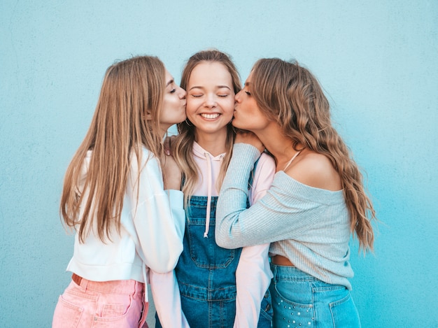 Portrait of  sexy carefree women posing in the street.positive models kissing their friend in cheek