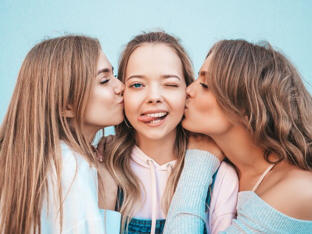 Portrait of  Sexy carefree women posing in the street.Positive models kissing their friend in cheek