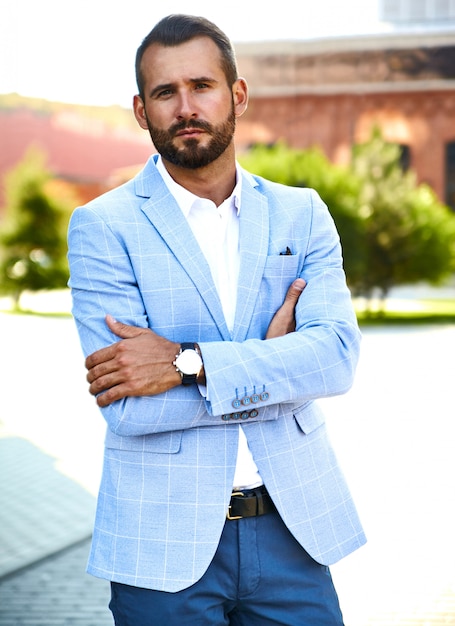 Il ritratto del modello bello sexy dell'uomo d'affari di modo si è vestito in vestito blu elegante che posa sul fondo della via. metrosexual