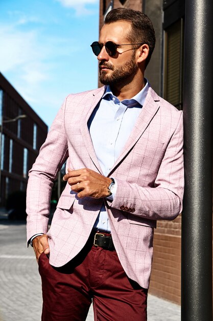 Portrait of sexy handsome fashion businessman model dressed in elegant suit posing on street background. Metrosexual