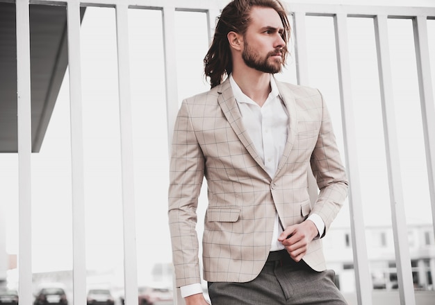 portrait of sexy handsome fashion male model man dressed in elegant beige checkered suit 