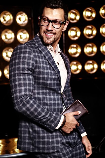 portrait of sexy handsome fashion male model man dressed in elegant suit on black studio lights background in glasses