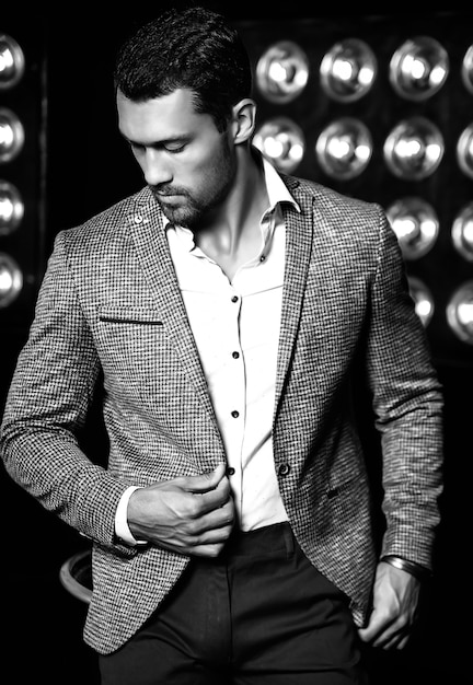 Free photo portrait of sexy handsome fashion male model man dressed in elegant suit on black studio lights background