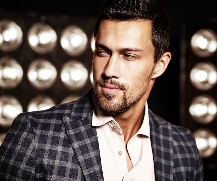 Free Photo portrait of sexy handsome fashion male model man dressed in elegant suit on black studio lights background