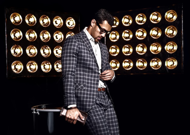 portrait of sexy handsome fashion male model man dressed in elegant suit studio lights background