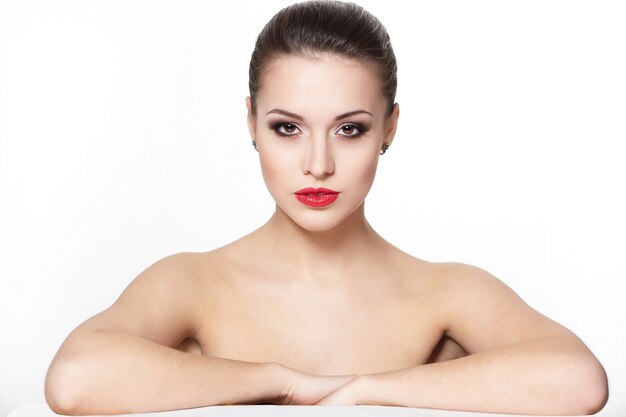 портрет сексуальной серьезной сидящей кавказской модели молодой женщины с гламурными красными губами, яркой косметикой, косметикой стрелы глаза, цветом чистоты. Идеально чистая кожа