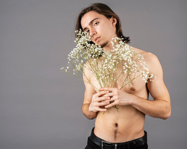 Portrait of shirtless man holding flowers