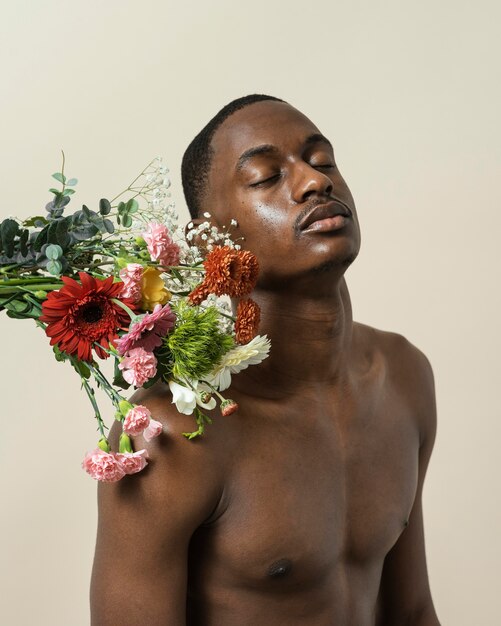 Portrait of shirtless man posing with bouquet of flowers