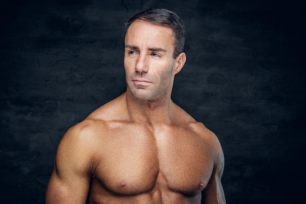 Portrait of shirtless middle age male with shaved chest  isolated with contrast illumination on grey background. Men's skin care.