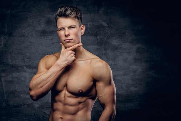 Portrait of shirtless strong muscular guy on grey background.