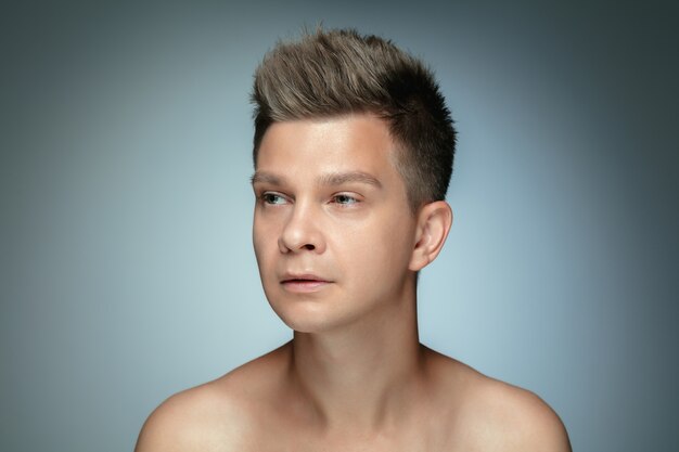 Portrait of shirtless young man isolated on grey studio wall