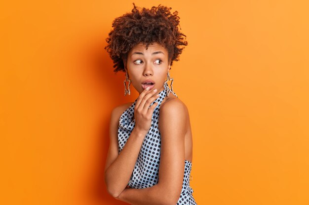 Portrait of shocked Afro American looks terrified behind back notices something amazing