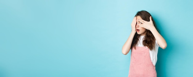 Free photo portrait of shocked brunette girl gasping startled covering eyes with hands but peeking through fing