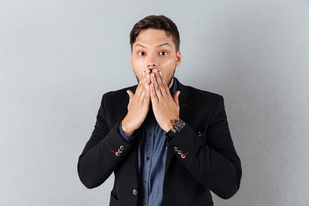 Portrait of a shocked businessman covering mouth