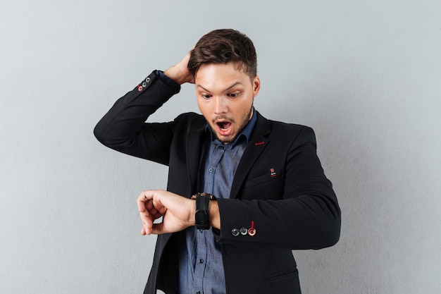 Portrait of a shocked businessman looking at wristwatch