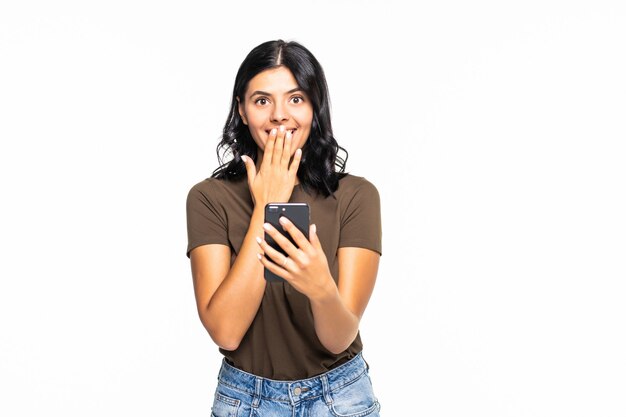 Portrait of a shocked businesswoman using mobile phone isolated over white wall