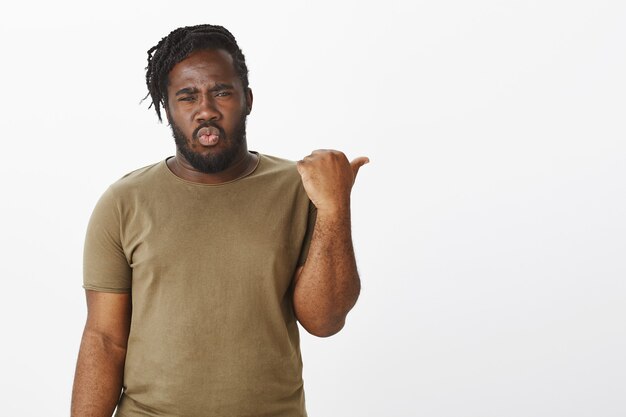 Portrait of shocked guy in a brown t-shirt posing against the white wall