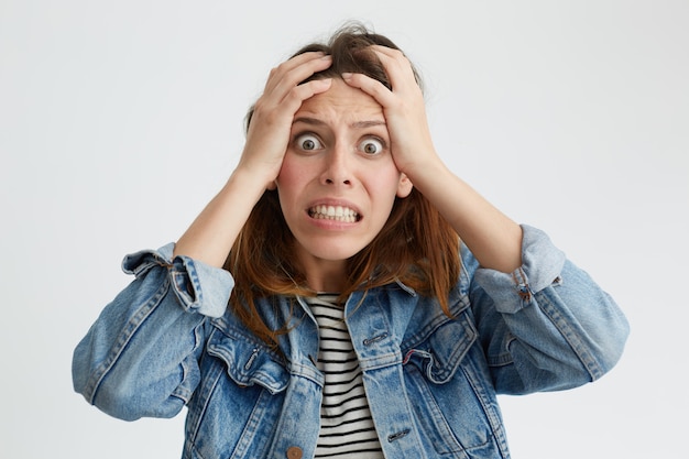 Free photo portrait of shocked terrified woman with dark eyes popped out clenching her teeth holding hands on head looking in despair isolated. woman having frustration