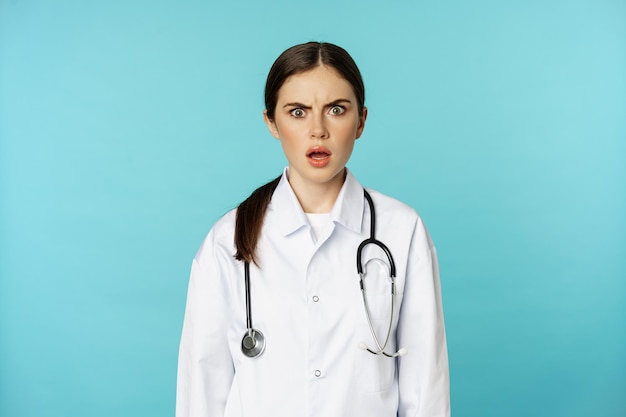 흰색 코트를 입고 걱정하고 혼란스러워 보이는 충격을 받은 여성 의사 여성 병원 인턴의 초상화...