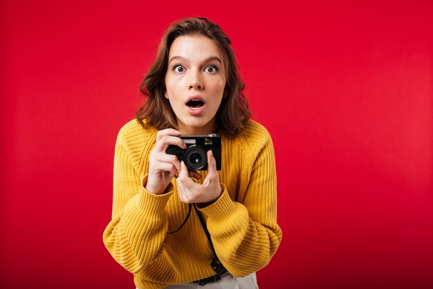 Portrait of a shocked woman holding vintage camera