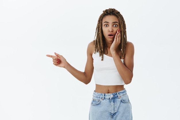 Portrait of shocked woman pointing at man got in trouble standing amazed and stunned indicating left holding palm on cheek and gasping worried