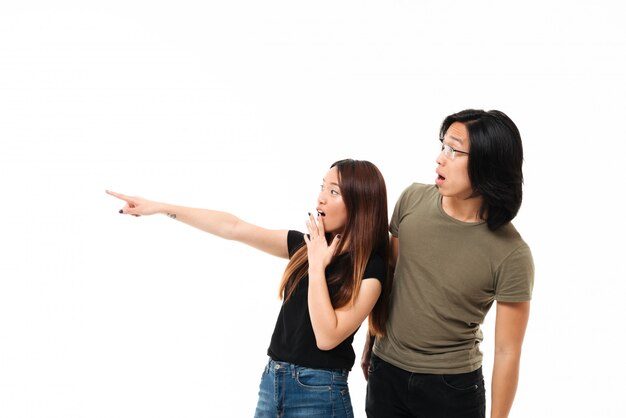 Portrait of a shocked young asian couple pointing