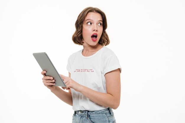 Portrait of a shocked young girl holding tablet computer