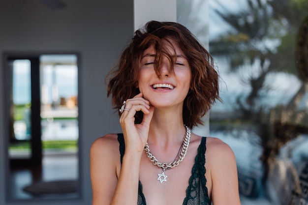 Free photo portrait of short hair brunette woman with chain on neck accessories in green lace lingerie outside villa