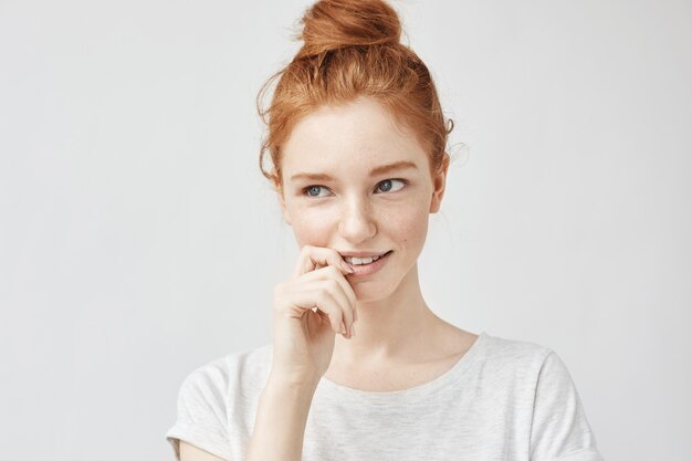 Portrait of shy beautiful woman with foxy hair and freckles smiling.